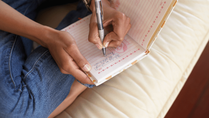 woman on bed writing in journal